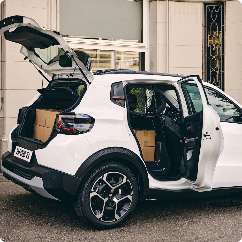 Vue arrière trois quarts de l’ë-C3 Van avec le hayon et la porte passager ouverts, illustrant l’accessibilité du chargement, la polyvalence de l’espace utile et son style inspiré des SUV.