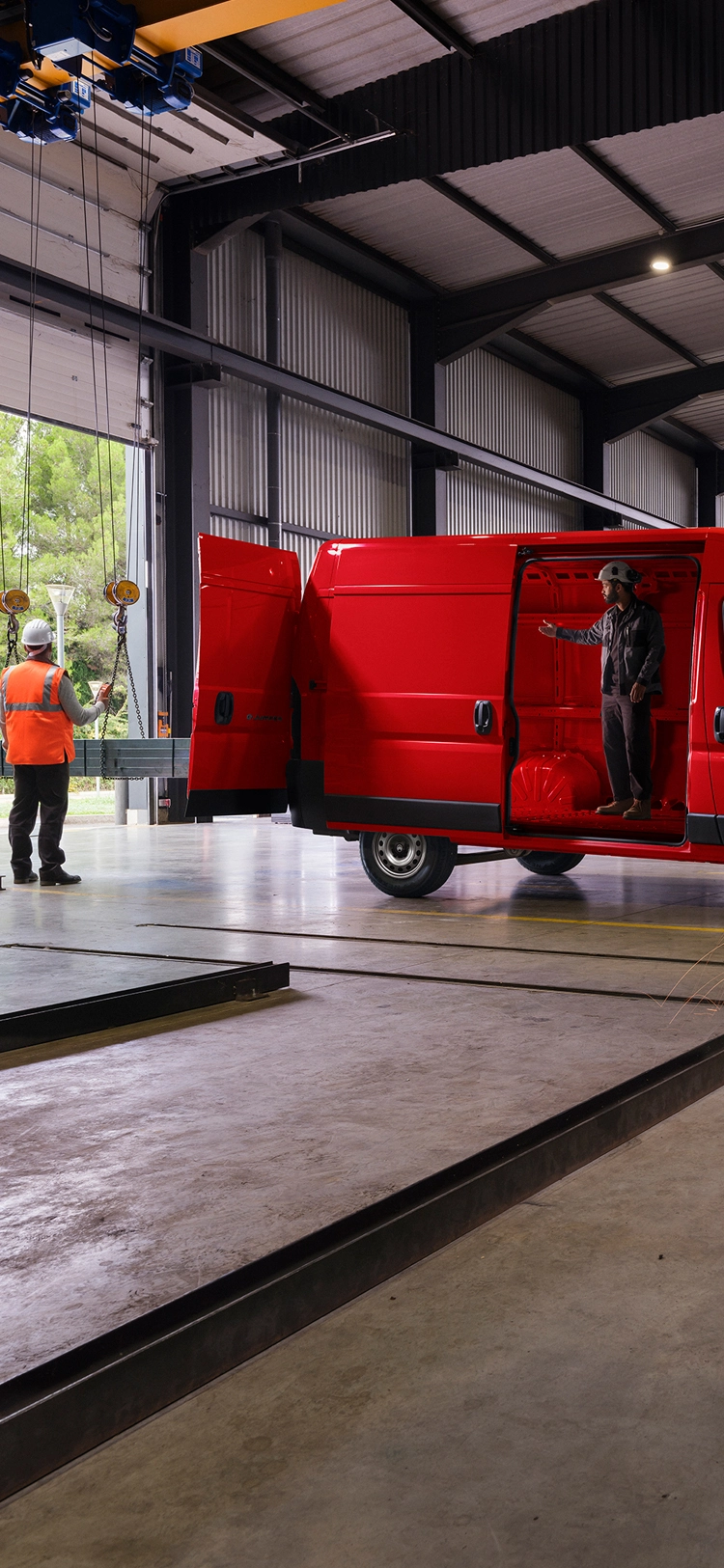 Zijaanzicht van een rode Citroën Jumper in een werkplaatsomgeving, waarbij het robuuste exterieurontwerp en de professionele bruikbaarheid goed tot hun recht komen.