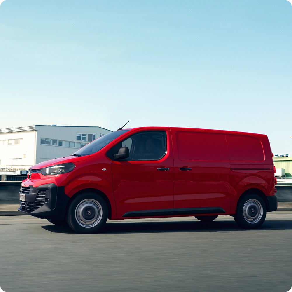 Side exterior view of a red Citroën ë‑Jumpy driving on the road, showing electric driving range, everyday practicality and confident professional presence.