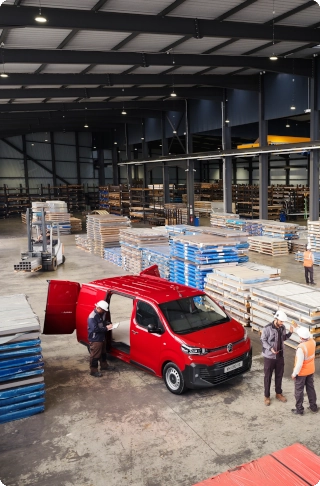 High‑angle exterior view of a red Citroën ë-Jumpy parked in an industrial warehouse, showing compact exterior dimensions, large cargo capacity and professional practicality.