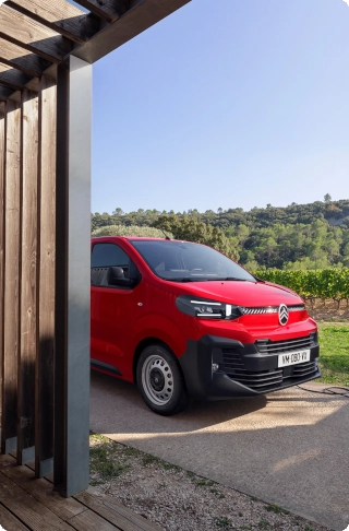 Rear three‑quarter exterior view of a red Citroën ë-Jumpy being loaded with goods, showing robust design, intensive daily use and practical cargo access.