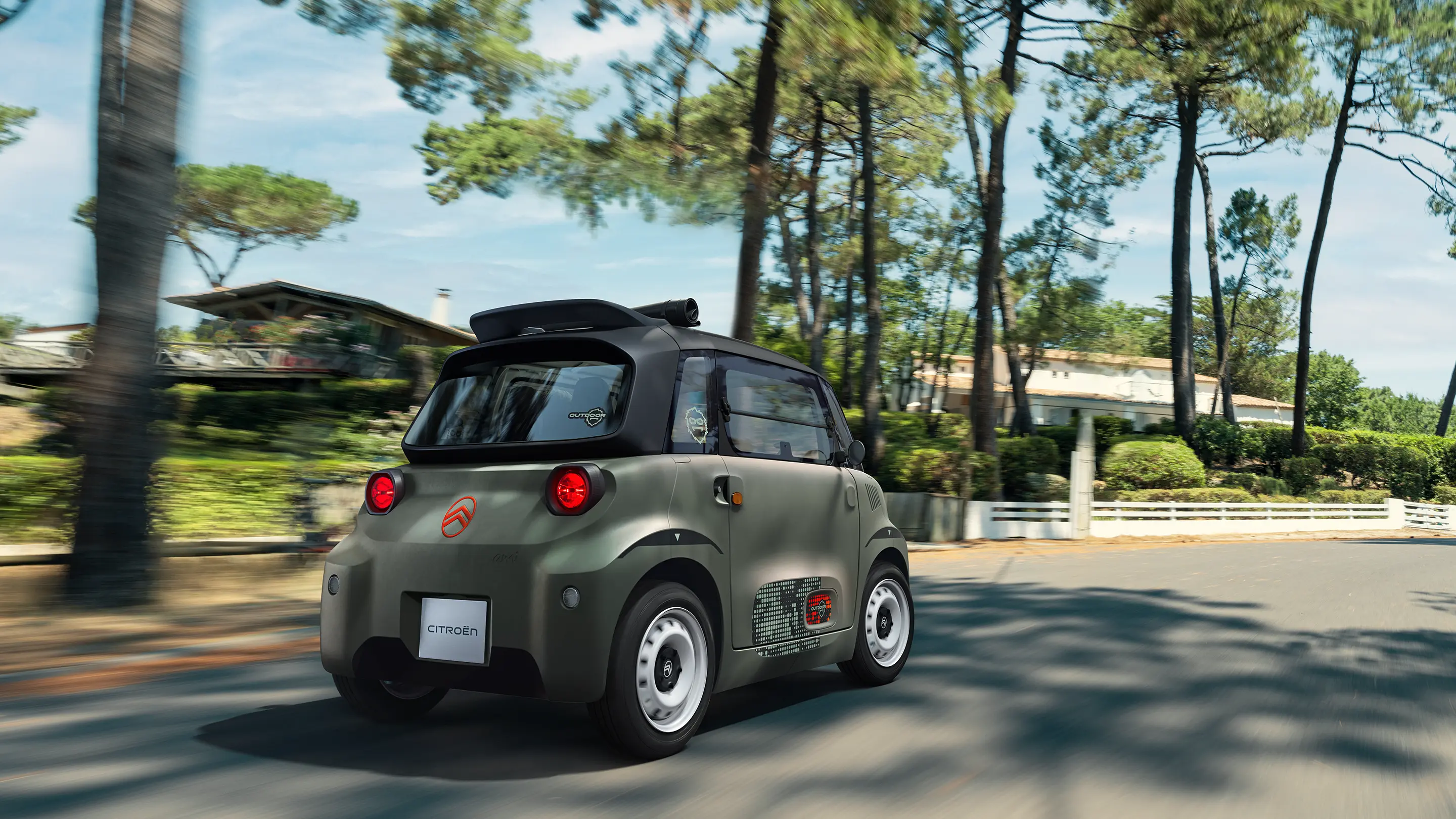 Vue arrière trois-quarts de Citroën Ami Outdoor avec toit ouvert présentant un véhicule urbain électrique roulant sur des routes forestières