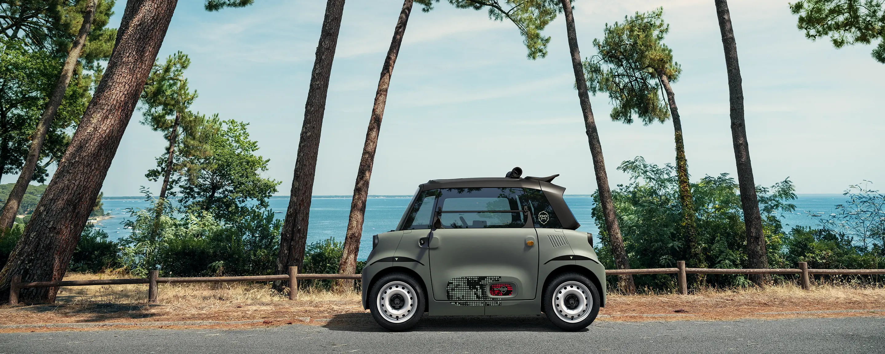 Vue de profil de Citroën Ami Outdoor avec toit ouvrant présentant un véhicule urbain électrique ultracompact en bord de mer