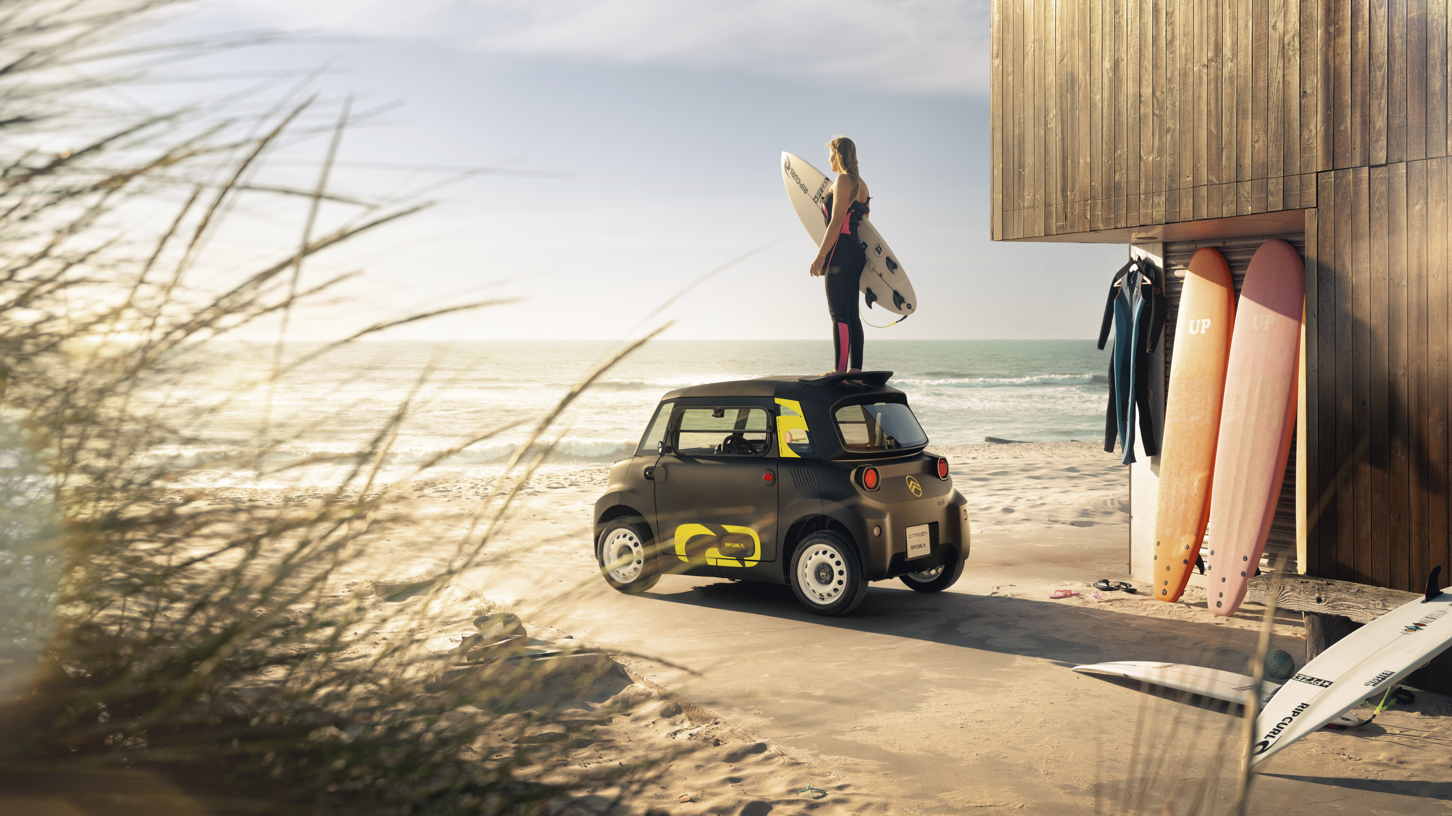 Lifestyle achteraanzicht op het strand van de Citroën Ami x Rip Curl elektrische wagen zonder rijbewijs, Citroën Ami staat voor surfvrijheid in stedelijke elektrische mobiliteit