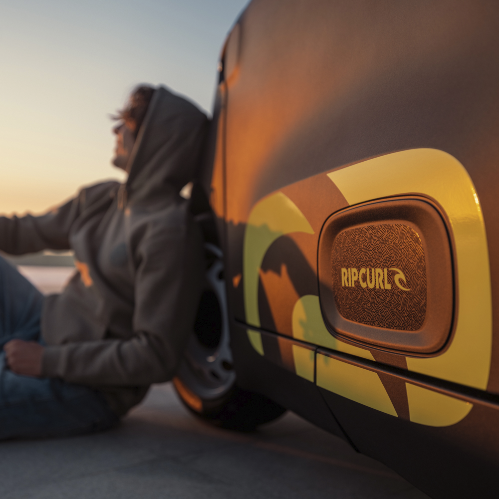 Close-up van de zijbadge van de Citroën Ami x Rip Curl elektrische wagen zonder rijbewijs, Rip Curl‑signatuur van de Citroën Ami voor een stedelijke elektrische wagen