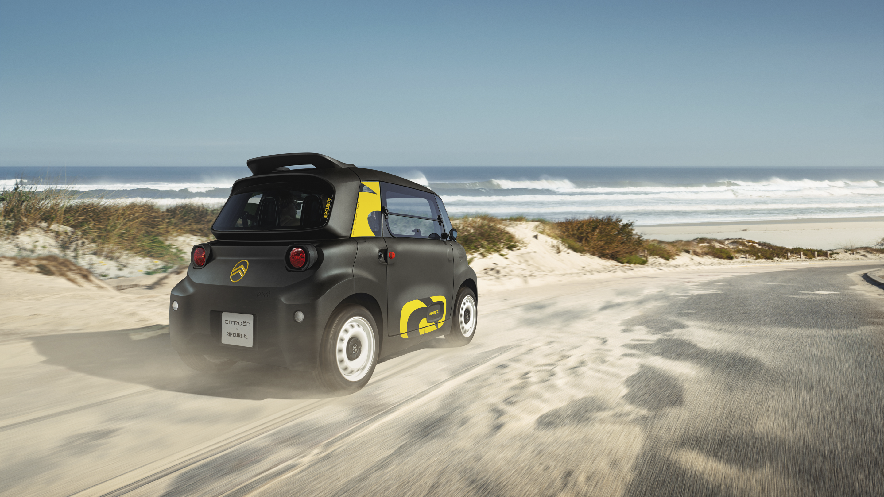 Actieaanzicht driekwart achteraanzicht van de Citroën Ami x Rip Curl elektrische wagen zonder rijbewijs, Citroën Ami staat voor vrijheid in stedelijke elektrische mobiliteit