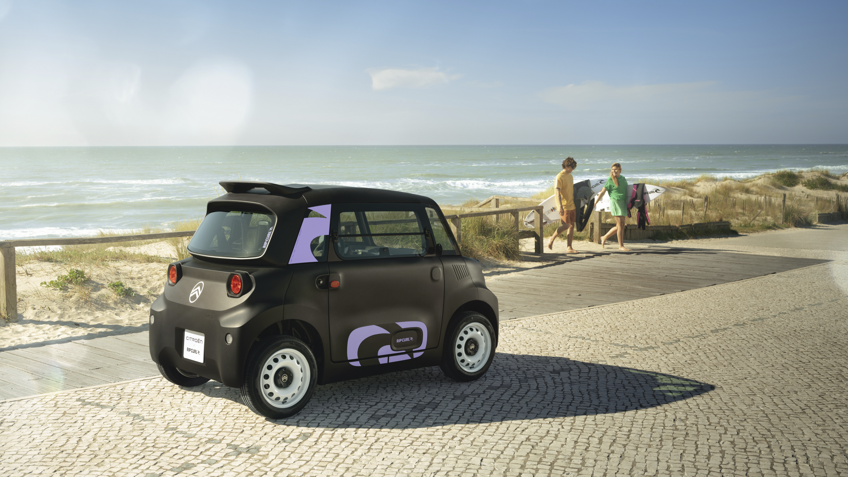 Driekwart achteraanzicht van de Citroën Ami x Rip Curl elektrische wagen zonder rijbewijs, Citroën Ami staat voor kustvrijheid in stedelijke elektrische mobiliteit
