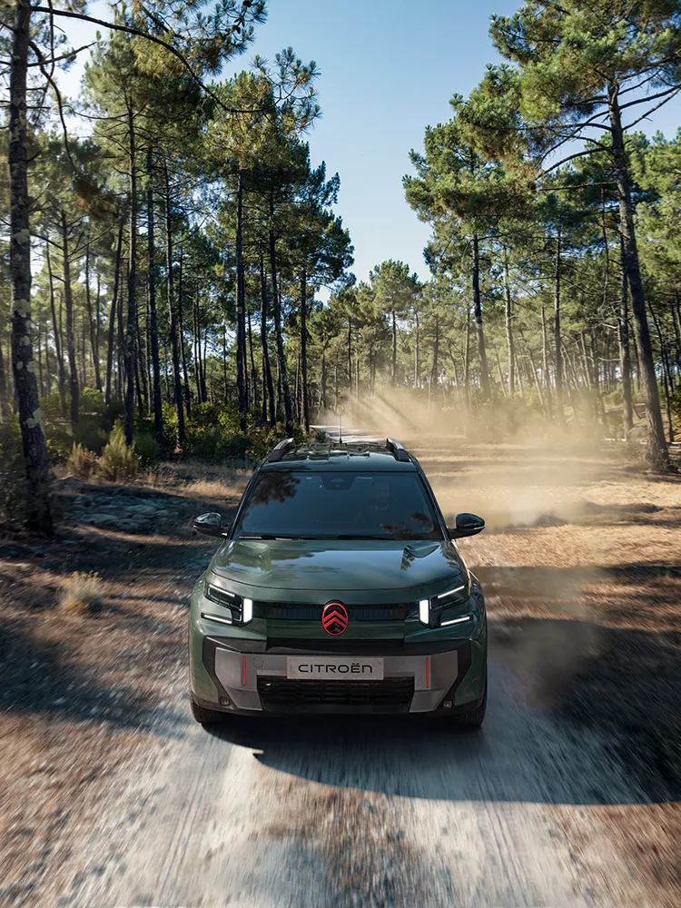 Vooraanzicht in vogelperspectief van de Citroën ë-C3 Aircross met LED-lichtsignatuur en Advanced Comfort, een gezins-SUV op een bospad