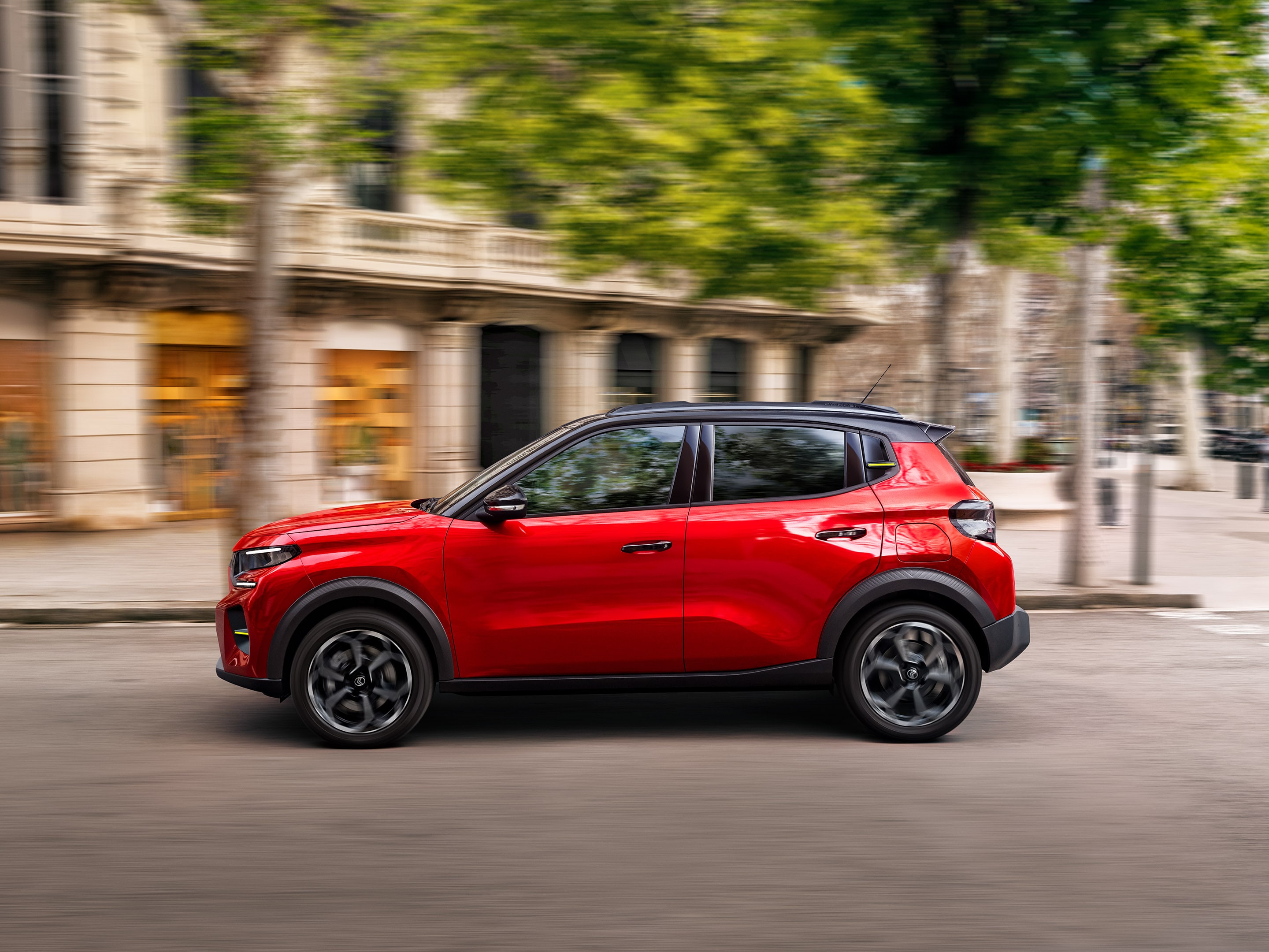 Zijaanzicht van de Citroën ë-C3 elektrische SUV die dynamisch stedelijk rijden toont voor soepele, praktische en betaalbare dagelijkse mobiliteit.
