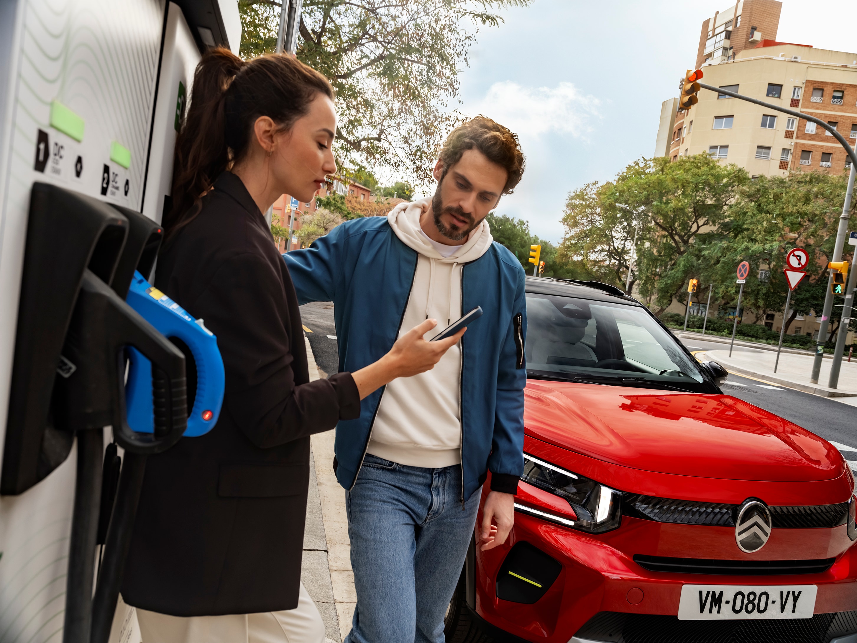 Straatlaadbeeld van de Citroën ë-C3 elektrische SUV met mensen die snel opladen voor gemakkelijke, efficiënte en betaalbare stedelijke mobiliteit.