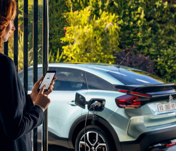 Женщина программирование Citroën ë-C4 Electric Recharge через свой смартфон