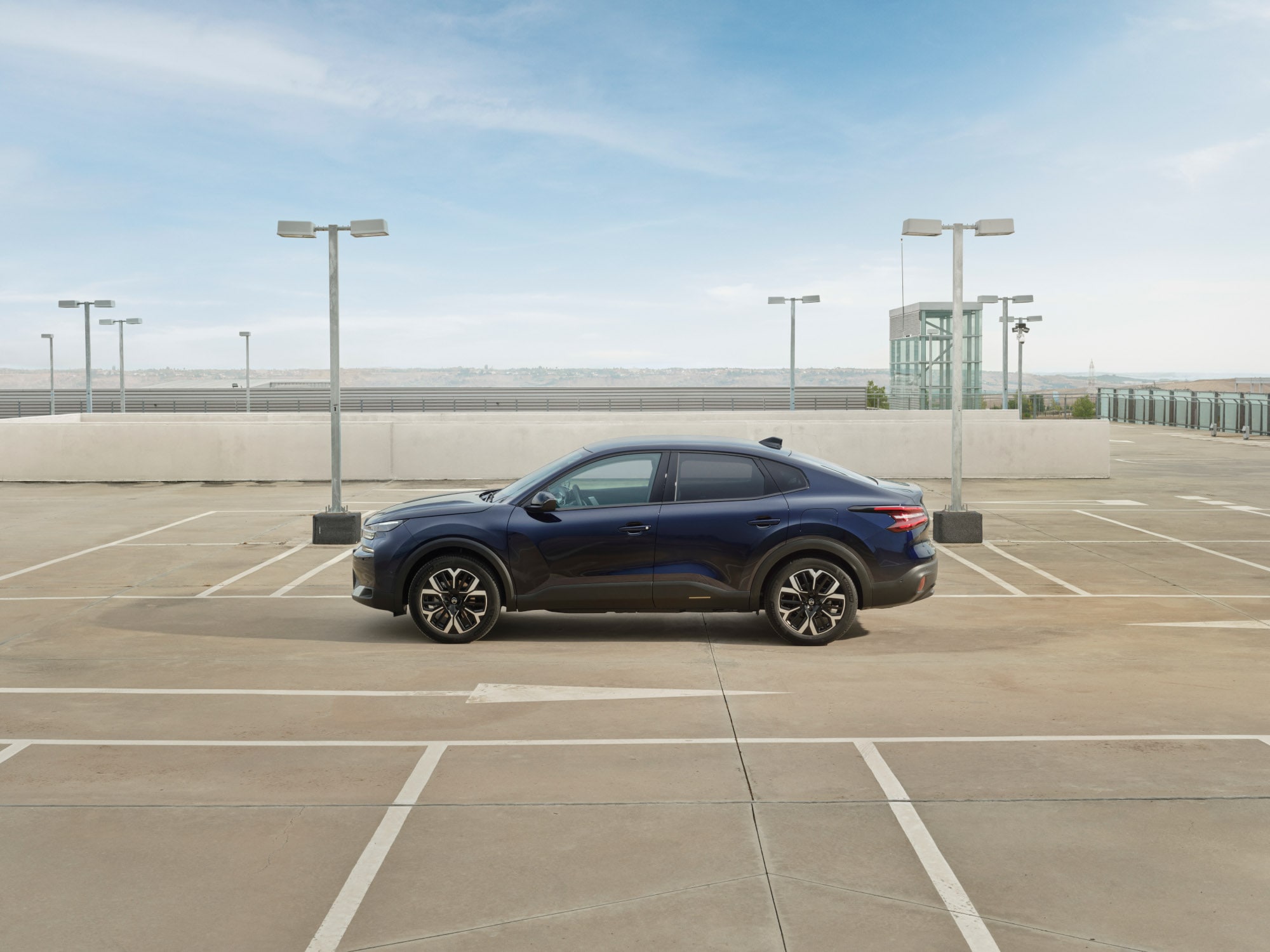 Vue latérale de la Citroën C4 X sur le parking sur le toit, mettant en valeur un profil fastback élégant pour une mobilité efficace et abordable