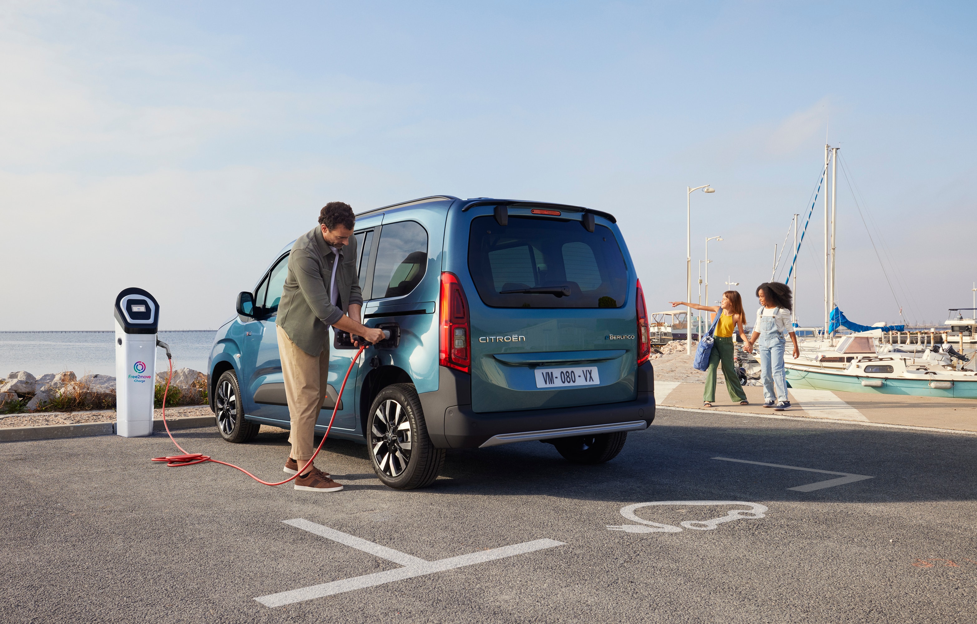 Achteraanzicht van driekwart Berlingo laadt bij een Free2move-station en toont veiligheid, efficiëntie, technologie en zelfverzekerd gebruik